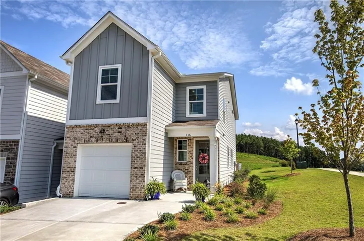 Two-story residence featuring a combination of brick and siding, an attached garage, and a concrete driveway