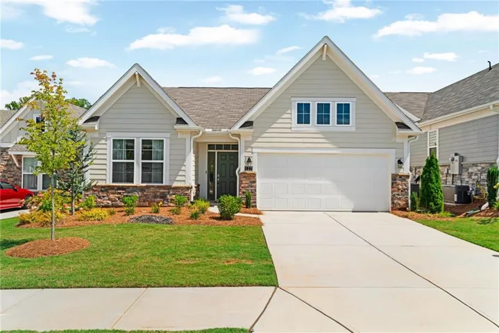 Craftsman-style exterior with stone veneer accents, light-colored siding, and a gabled roof