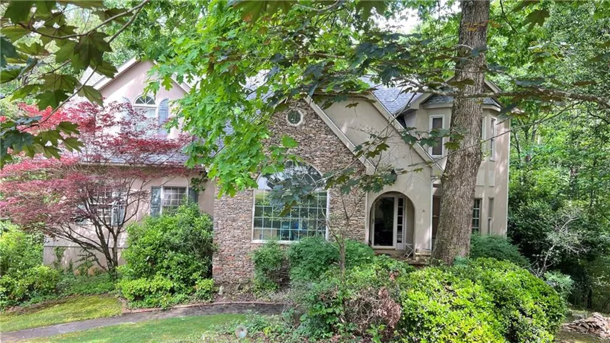 Stucco and stone facade with an arched entry and diverse fenestration