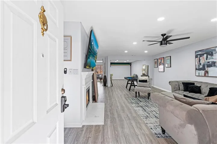 Wood-finish flooring throughout, recessed lighting, ceiling fan, fireplace with mantel, and a built-in pool table