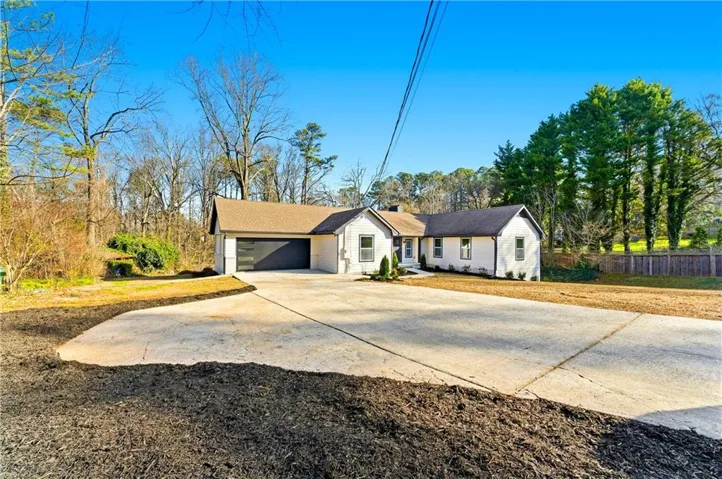 White exterior with dark trim accents, a dark garage door, and a brown roof