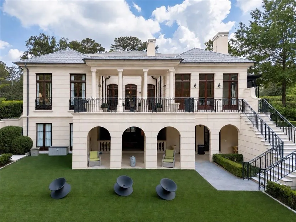 Stately stone exterior featuring a columned balcony with wrought iron railing, arched ground-level loggia, and exterior staircase with matching wrought iron balustrade