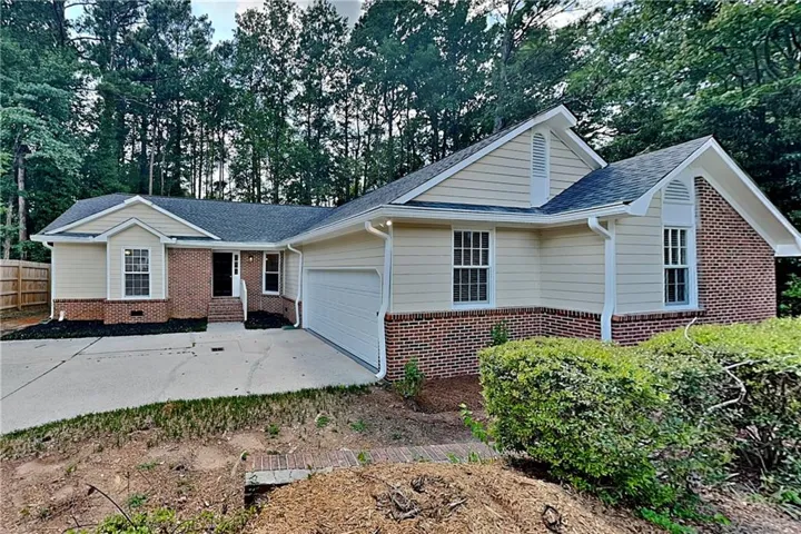 Single-story home featuring a combination of brick and siding, an attached garage, and a concrete driveway