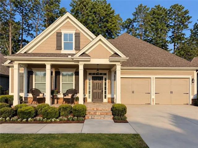 Pitched roofline, covered front porch, columned entry, two-car garage, and established landscaping