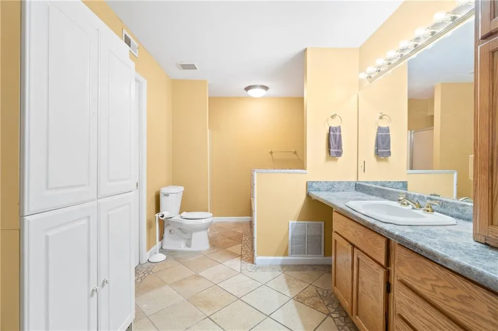 Bathroom with tile patterned floors, vanity, a shower with shower door, and toilet
