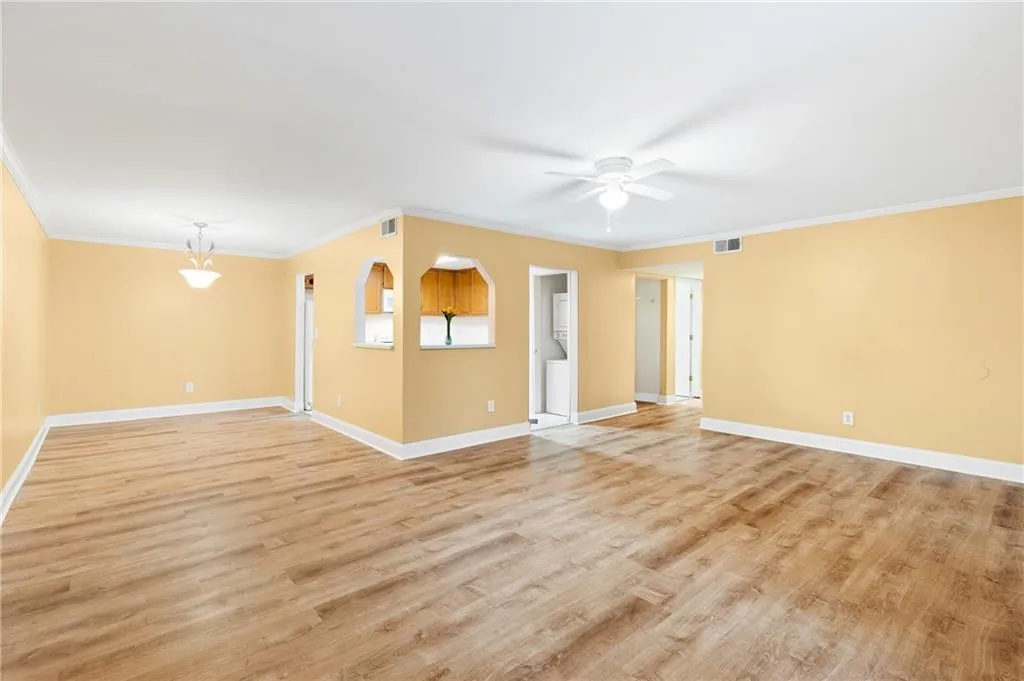 Empty room with ceiling fan, ornamental molding, and light wood-type flooring