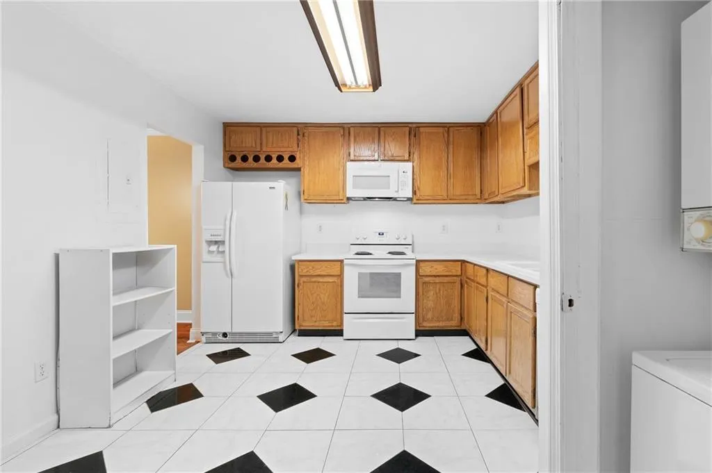 Kitchen featuring white appliances, washer / clothes dryer, and light tile patterned flooring