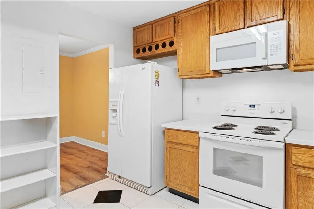 Kitchen featuring light wood-type flooring, white appliances, electric panel, and crown molding