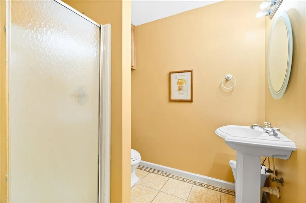 Bathroom with tile patterned floors, a shower with shower door, and toilet