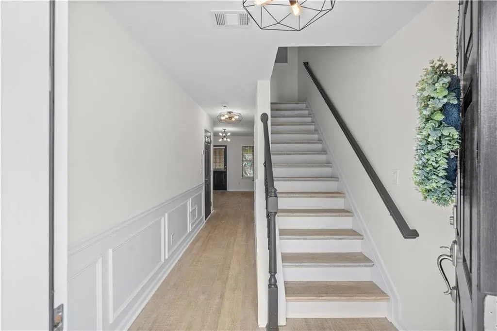 Welcoming foyer with classic wainscoting, updated lighting and an open rail staircase with iron spindles.
