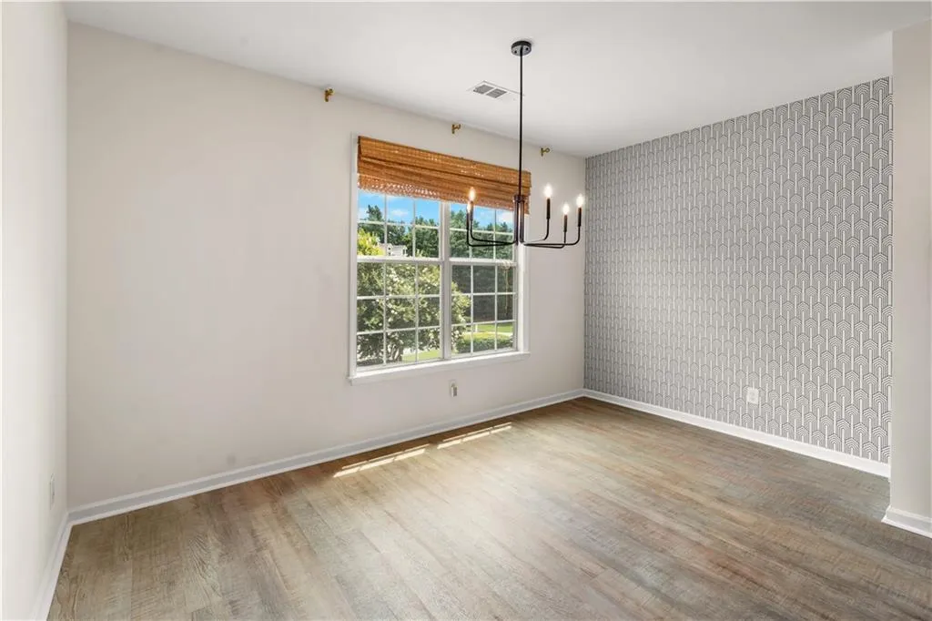 Bright, naturally lit dining space featuring luxury vinyl plank flooring, neutral walls, and a large window with views to the cul-de-sac.