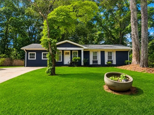 Contemporary ranch-style residence featuring a dark blue facade with white trim, white front door, and white louvered shutters
