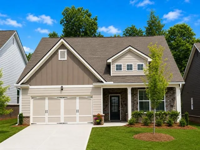 Contemporary single-story residence with a two-car garage, stone and siding exterior, front porch with columns, and dormer window detail