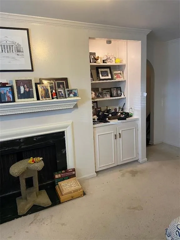 Bar featuring arched walkways, light carpet, and crown molding
