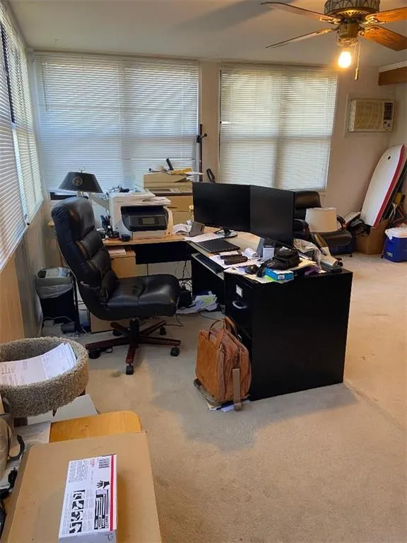 Carpeted home office with plenty of natural light, ceiling fan, and an AC wall unit
