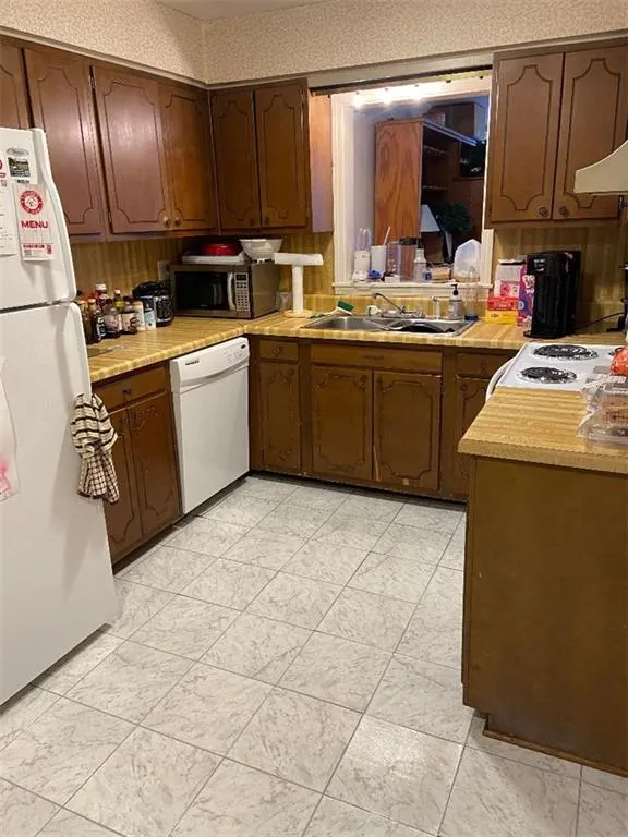 Kitchen with white appliances, light countertops, and extractor fan