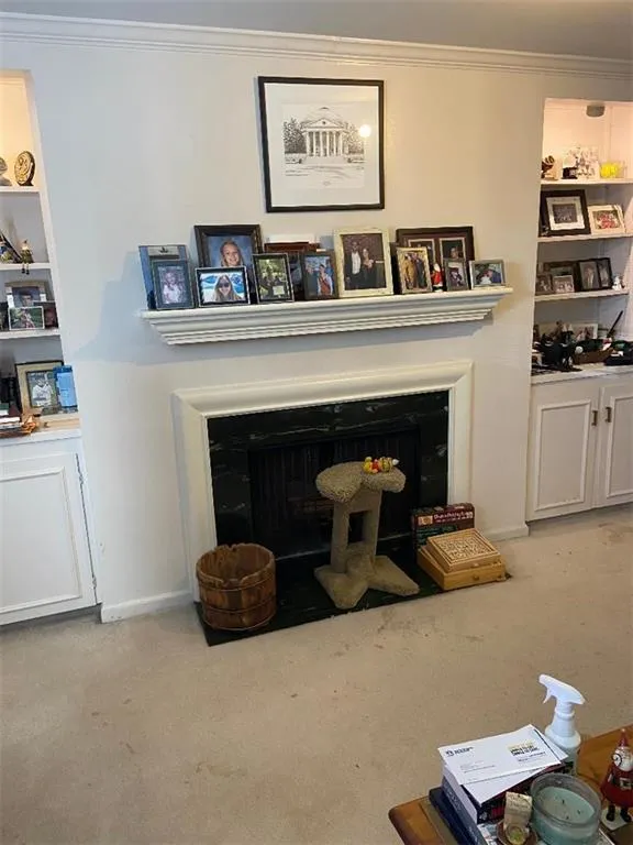 Detailed view of carpet flooring, crown molding, and a fireplace