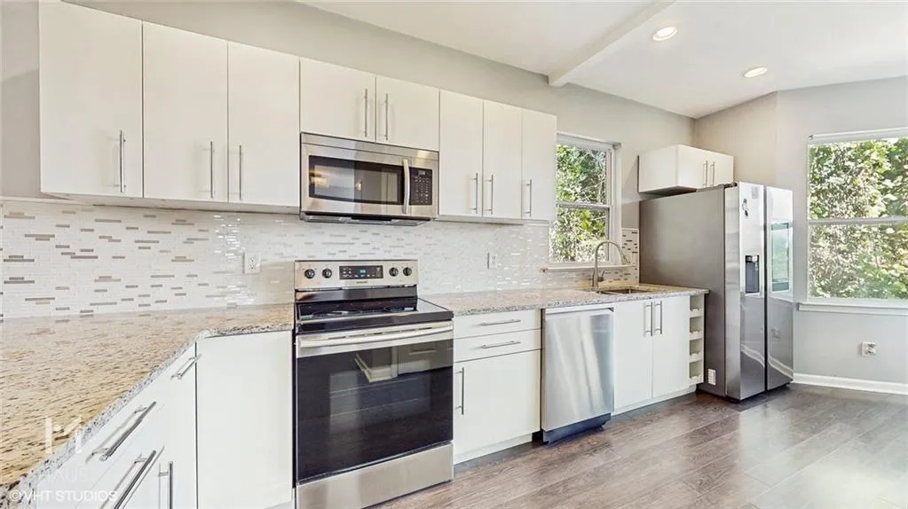Kitchen with stainless steel appliances, dark wood finished floors, light stone counters, recessed lighting, and decorative backsplash
