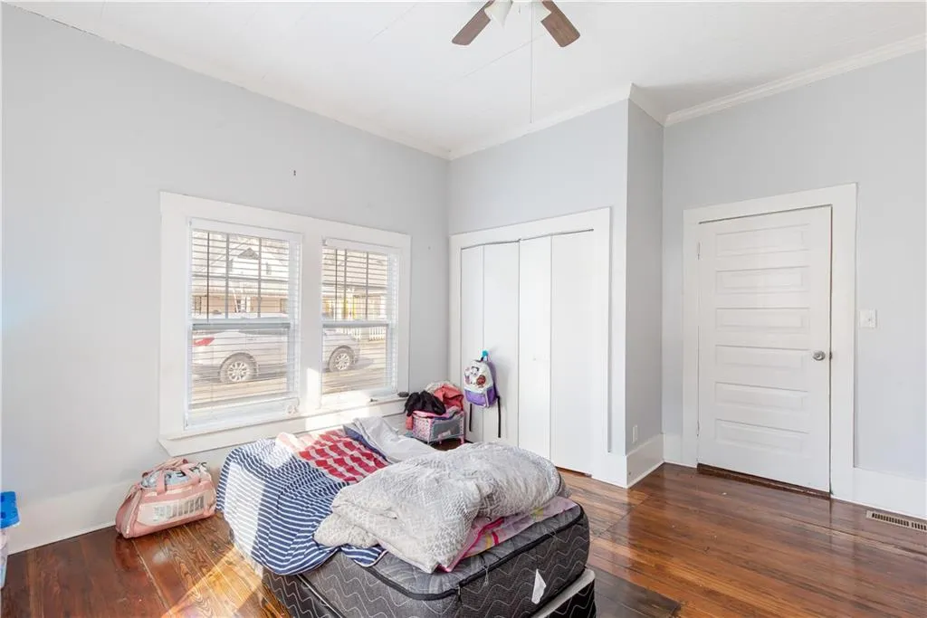 Bedroom with dark hardwood / wood-style floors, a closet, crown molding, and ceiling fan