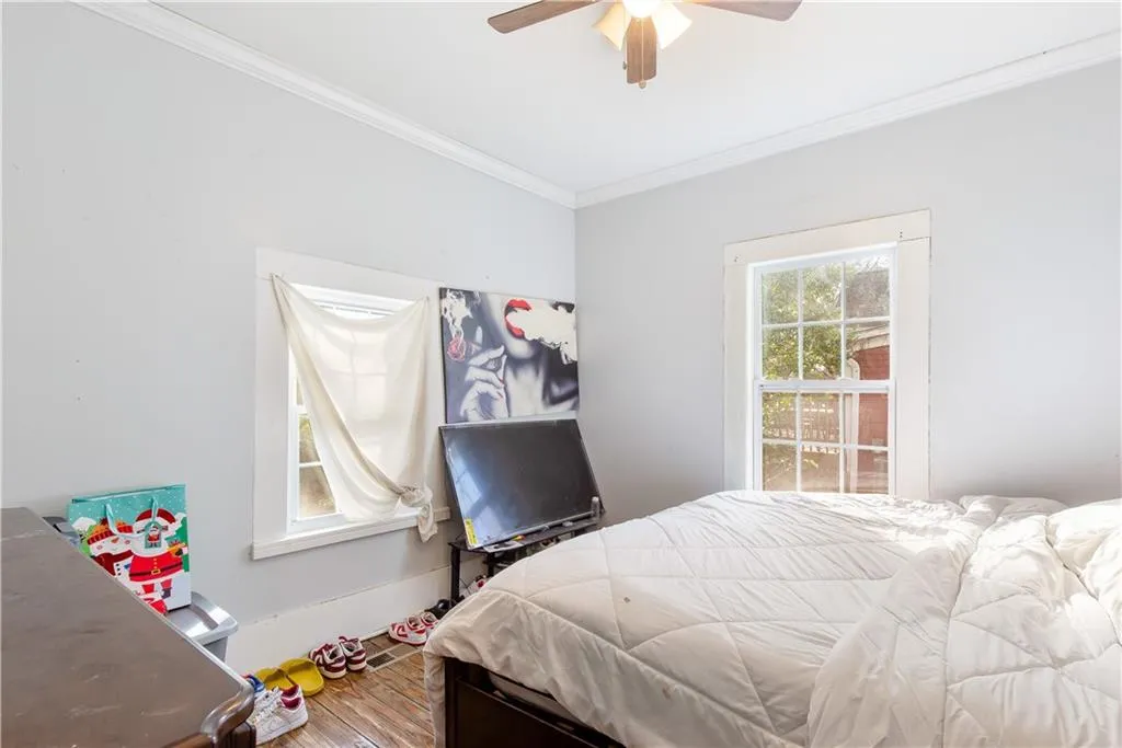 Bedroom with wood-type flooring, crown molding, and ceiling fan