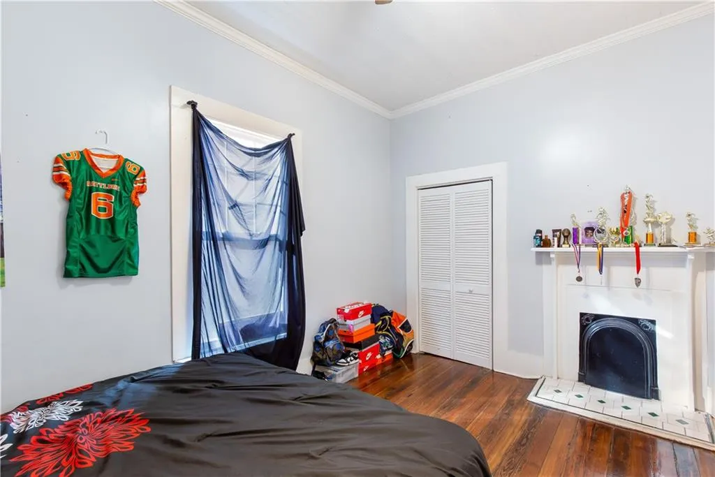 Bedroom with crown molding, a closet, and dark wood-type flooring