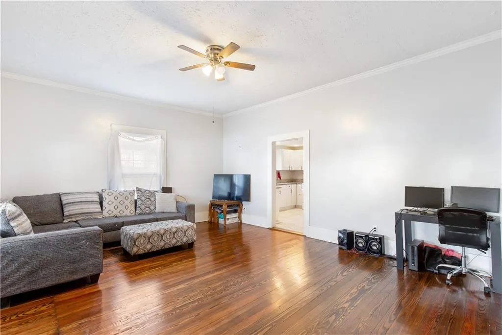Living room featuring ornamental molding, a textured ceiling, dark wood-type flooring, and ceiling fan