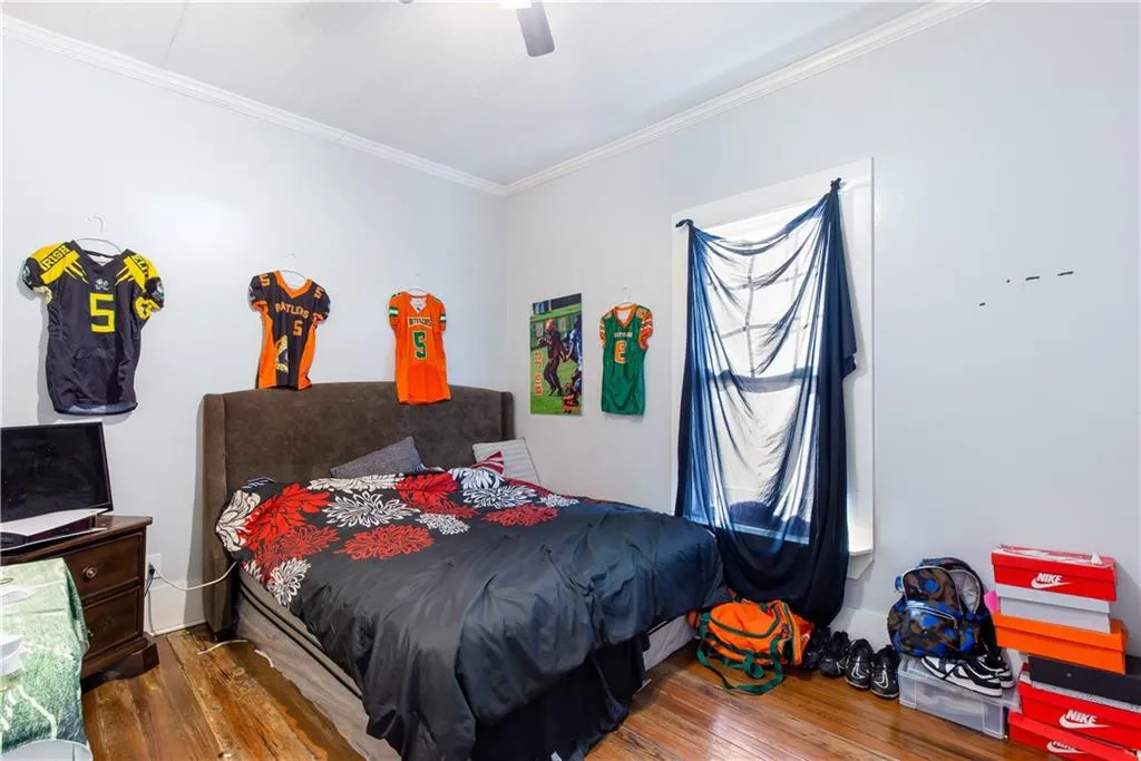 Bedroom with ornamental molding, dark hardwood / wood-style flooring, and ceiling fan