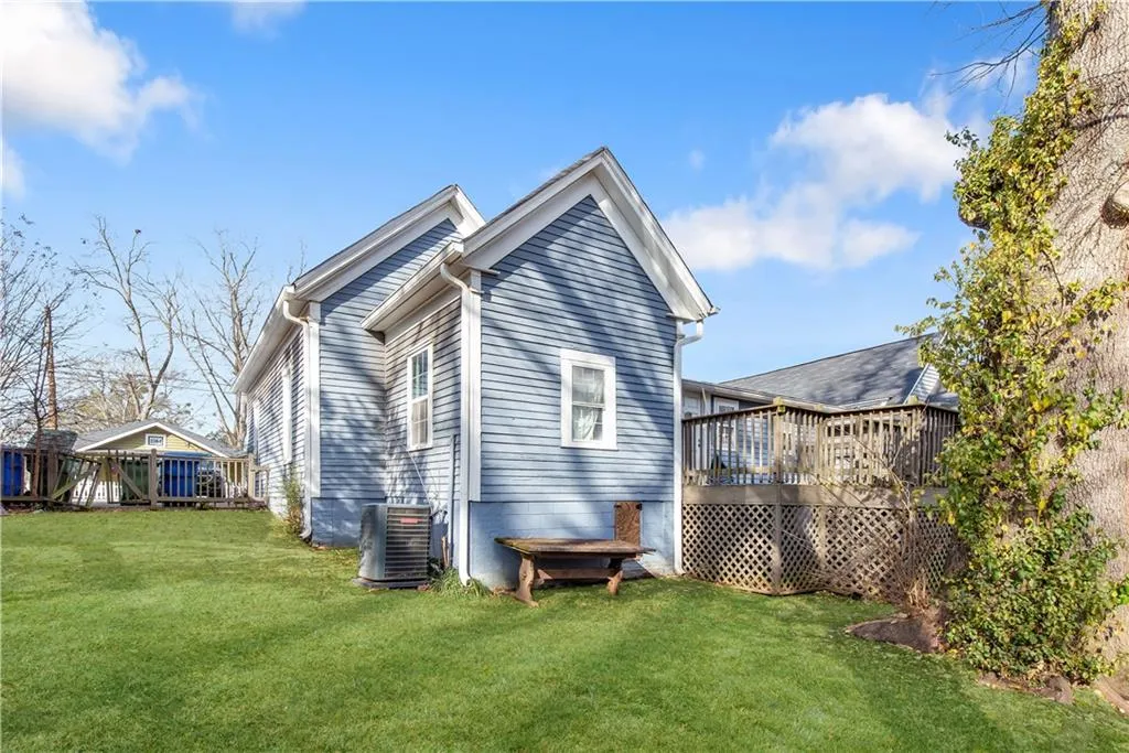 View of home's exterior featuring a wooden deck, a yard, and central AC