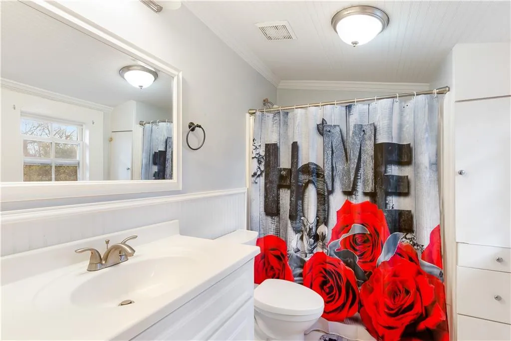 Bathroom featuring crown molding, toilet, lofted ceiling, and oversized vanity
