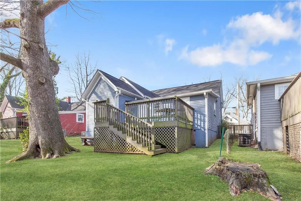 Rear view of property featuring a wooden deck and a lawn