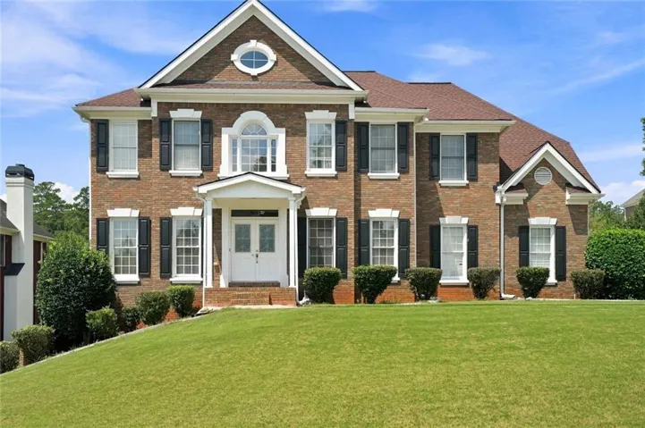 Brick exterior with white trim, black shutters, and an arched transom window above the double front doors