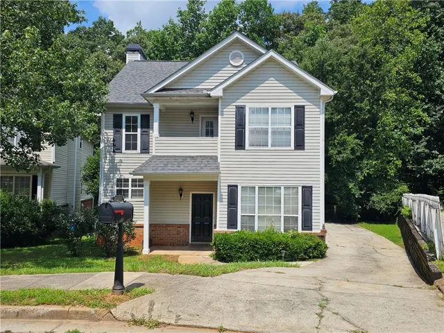 Two-story residence featuring light-colored siding, black shutters, and a dark asphalt shingle roof