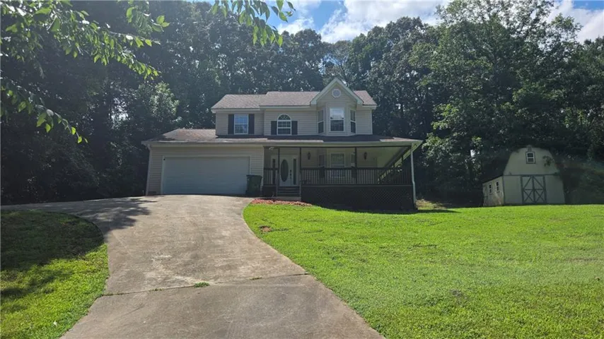 Two-story residence with an attached garage, covered front porch, and a dedicated storage shed