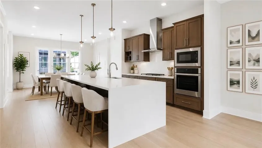 Quartz-top kitchen island, wood-finish flooring, stainless steel appliances, recessed lighting, and pendant lights