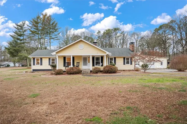 Ranch-style residence featuring yellow siding, a covered porch with white columns, and dark window shutters