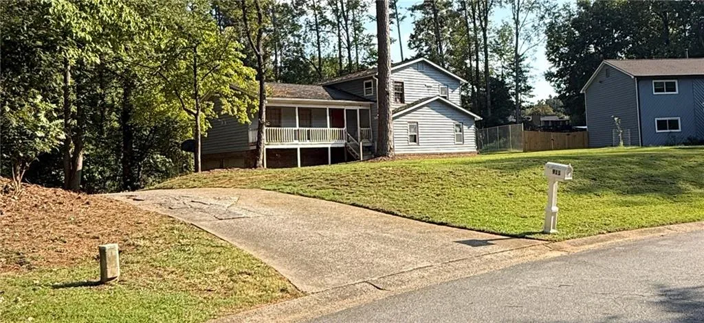 Split-level residence featuring gray siding and a covered front porch with white railing