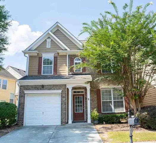 Two-story residence featuring a brick and siding exterior, an attached garage, a front entry with sidelights, and mature landscaping