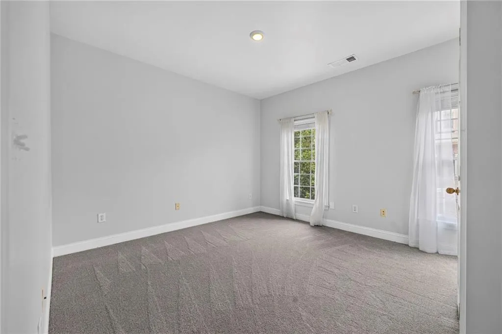 Neutral-toned room featuring a single window, recessed lighting, and grey carpet flooring