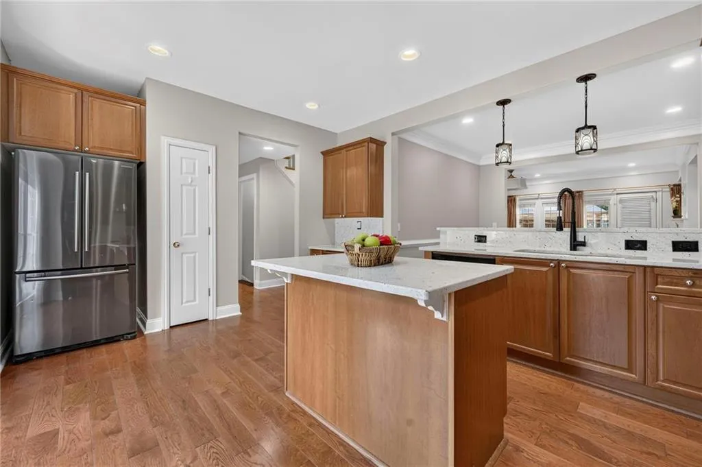 Kitchen featuring wood-finish flooring, light wood cabinetry, white countertops, and a central island