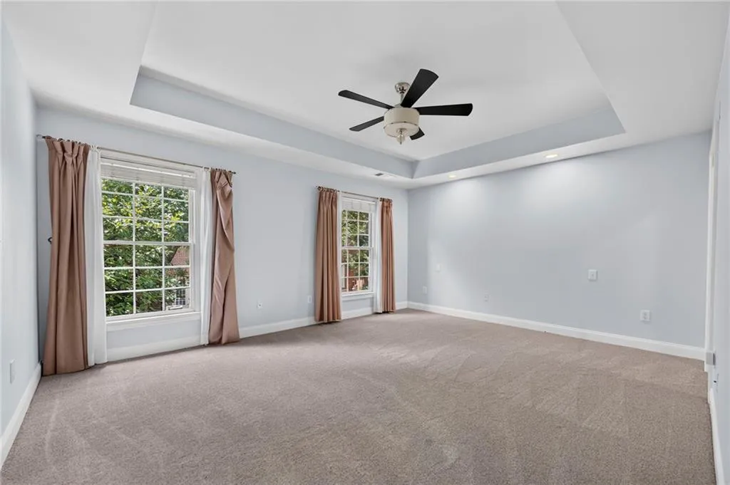 Spacious room featuring a tray ceiling, recessed lighting, and a ceiling fan