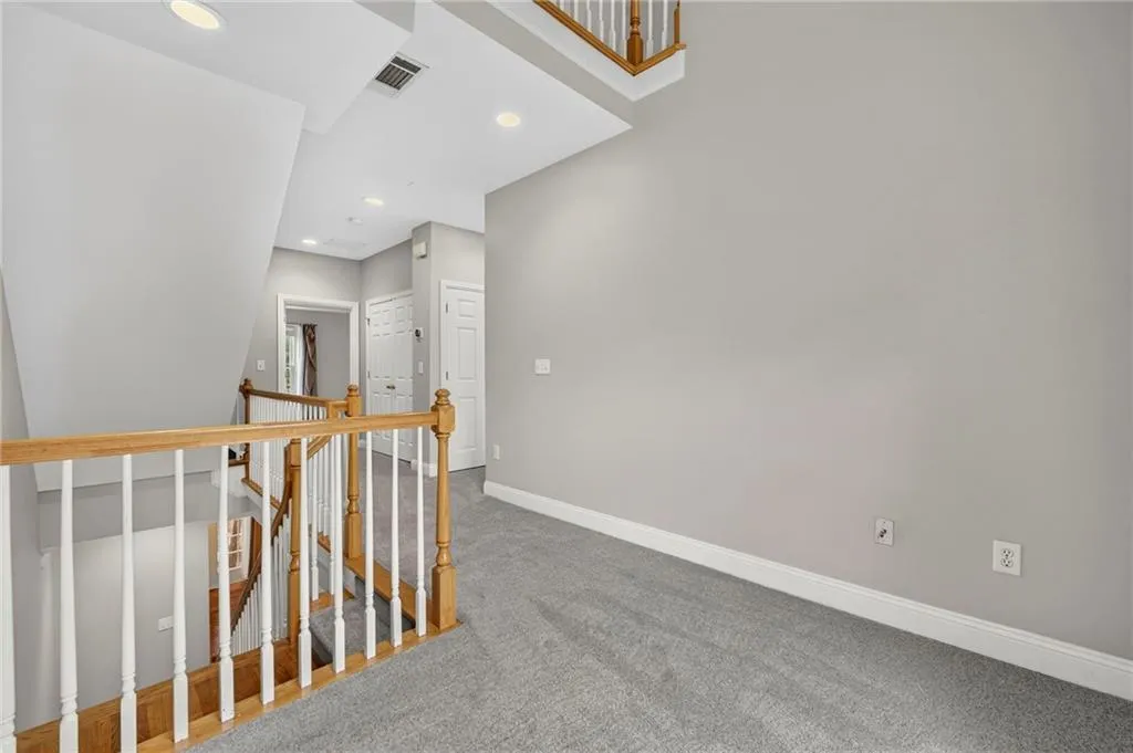 Upper-level hallway featuring light gray carpeting, white baseboards, and neutral wall paint