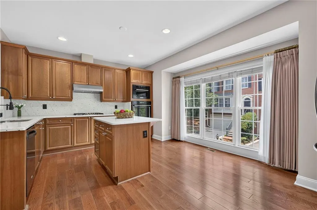 Kitchen featuring wood cabinetry, a center island with countertop, stainless steel appliances, and wood-finish flooring