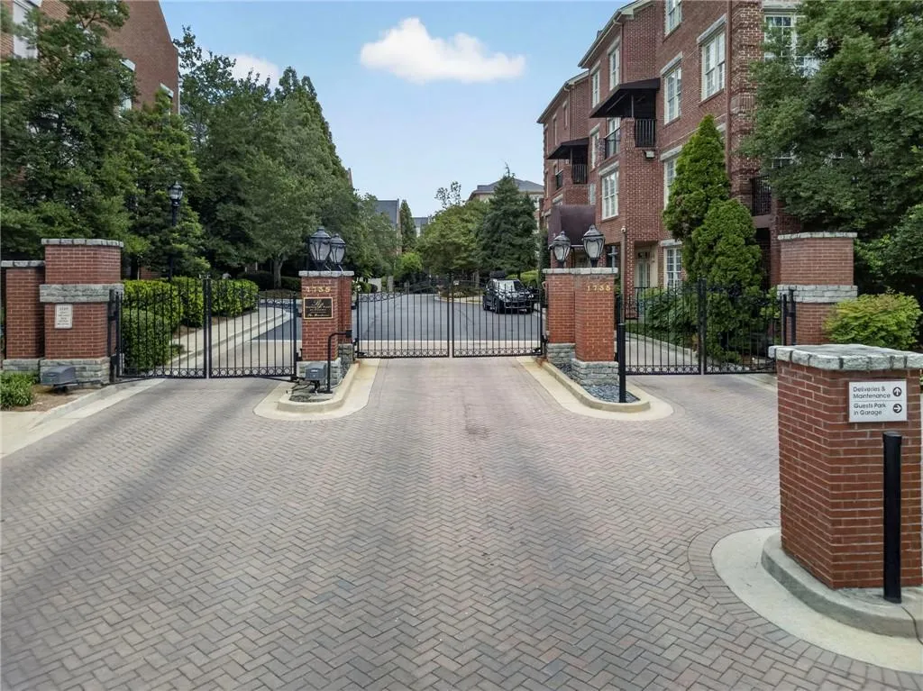 Brick paver entrance with decorative iron gates, flanked by brick columns with stone caps and integrated lighting