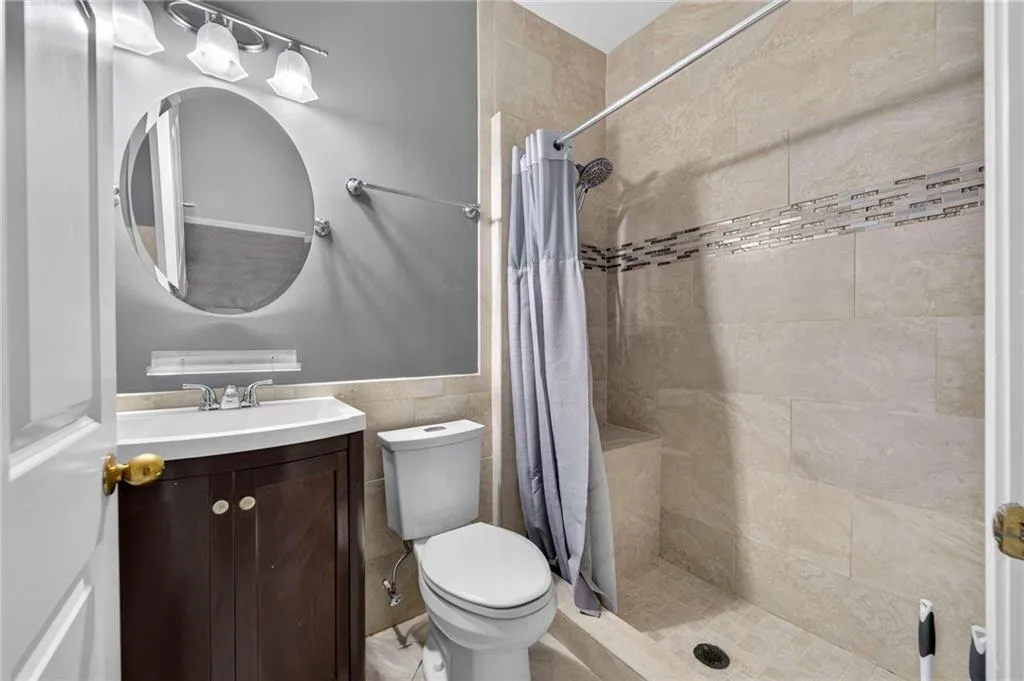 Full bathroom featuring a walk-in shower with light-toned wall tile, a decorative tile accent band, and a built-in shower bench