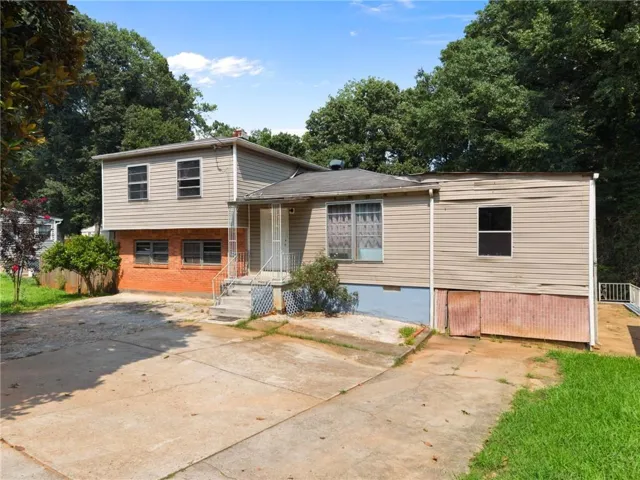 Property exterior with mixed siding and brick elements, concrete driveway, and mature landscaping