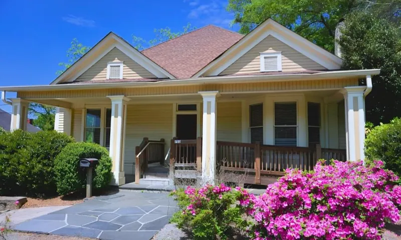 Covered porch with square columns, gabled dormer, and a stone walkway
