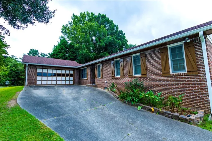 Brick exterior featuring a two-car garage with paneling and transom-style windows