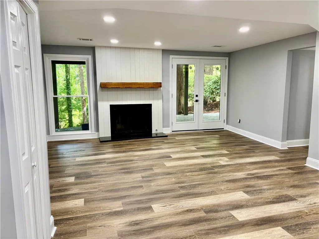 Unfurnished living room with baseboards, plenty of natural light, wood finished floors, a fireplace, and recessed lighting