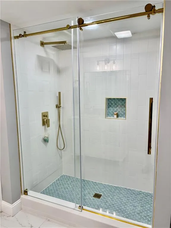 Full bath with a stall shower and marble finish floors