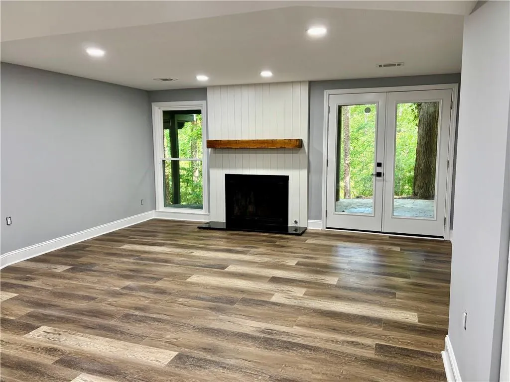 Unfurnished living room with healthy amount of natural light, french doors, baseboards, and recessed lighting